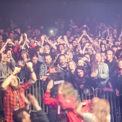 Tłum ludzi na festiwalu w Bieszczadach, z rękami w górze, cieszący się muzyką.