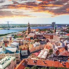 Widok na Rygę z lotu ptaka, z rzeką i mostem w tle. Widać urokliwe kamienice i place, idealne miejsca, by zastanowić się, co zjesc w Rydze.