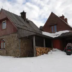 Kamienna Chatka Puchatka w Bieszczadach, zasypana śniegiem, z drewnianym zadaszeniem i stosem drewna.