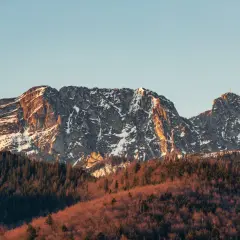 Giewont ośnieżony, z krzyżem na szczycie, w złotym świetle zachodzącego słońca. Czy ciężko wejść na Giewont? Widok zapiera dech w piersiach.