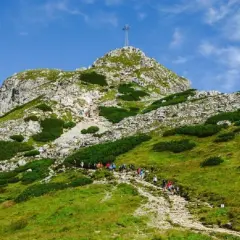 Grupa turystów wspina się kamienistym szlakiem na szczyt Giewontu w Tatrach. Góra przypomina śpiącego rycerza.