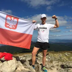Mężczyzna z polską flagą na szczycie górskim, świętuje zdobycie Korony Gór Polskich. Rekordowe osiągnięcie!