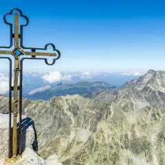 Krzyż na szczycie Gerlach bez przewodnika. Majestatyczne Tatry rozciągają się pod błękitnym niebem.