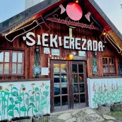 Karczma "Siekierezada" w Polańczyku, Bieszczady. Drewniana chata z neonem, rzeźbami wilków i malowidłami słoneczników.