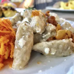 Kluski śląskie z twarogiem i skwarkami, podane z tartą marchewką.