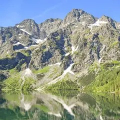 Majestatyczne Tatry odbijają się w spokojnej tafli jeziora. Ciekawe ciekawostki o tatrach czekają na odkrycie!
