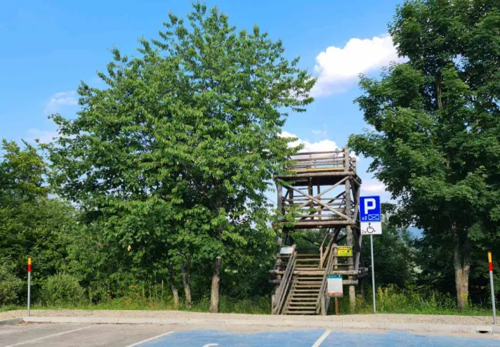 Drewniana wieża widokowa Szczerbanówka z widocznymi schodami i parkingiem.