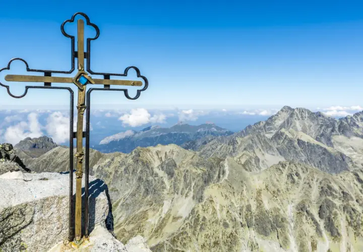Krzyż na szczycie Gerlach bez przewodnika. Majestatyczne Tatry rozciągają się pod błękitnym niebem.