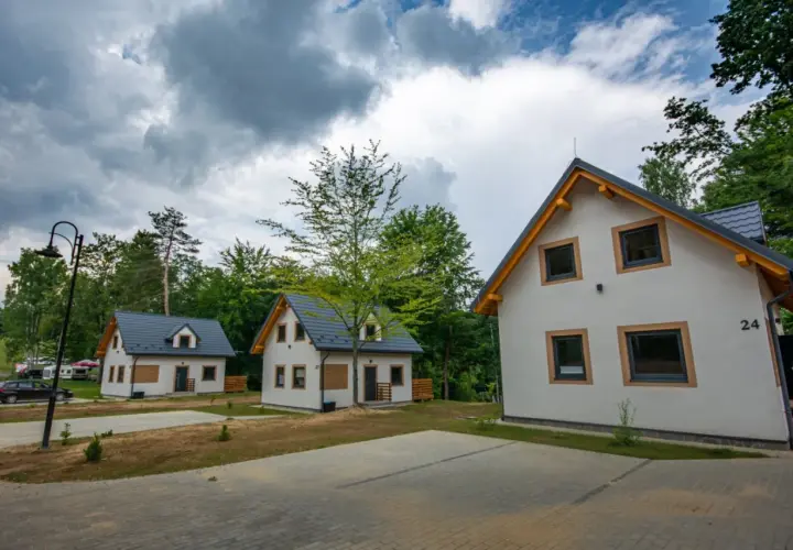 Nowe domki letniskowe, idealne na przystań wyspa energetyk. W tle las i chmury.
