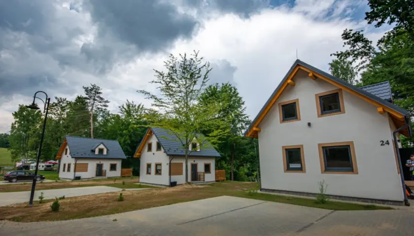 Nowe domki letniskowe, idealne na przystań wyspa energetyk. W tle las i chmury.