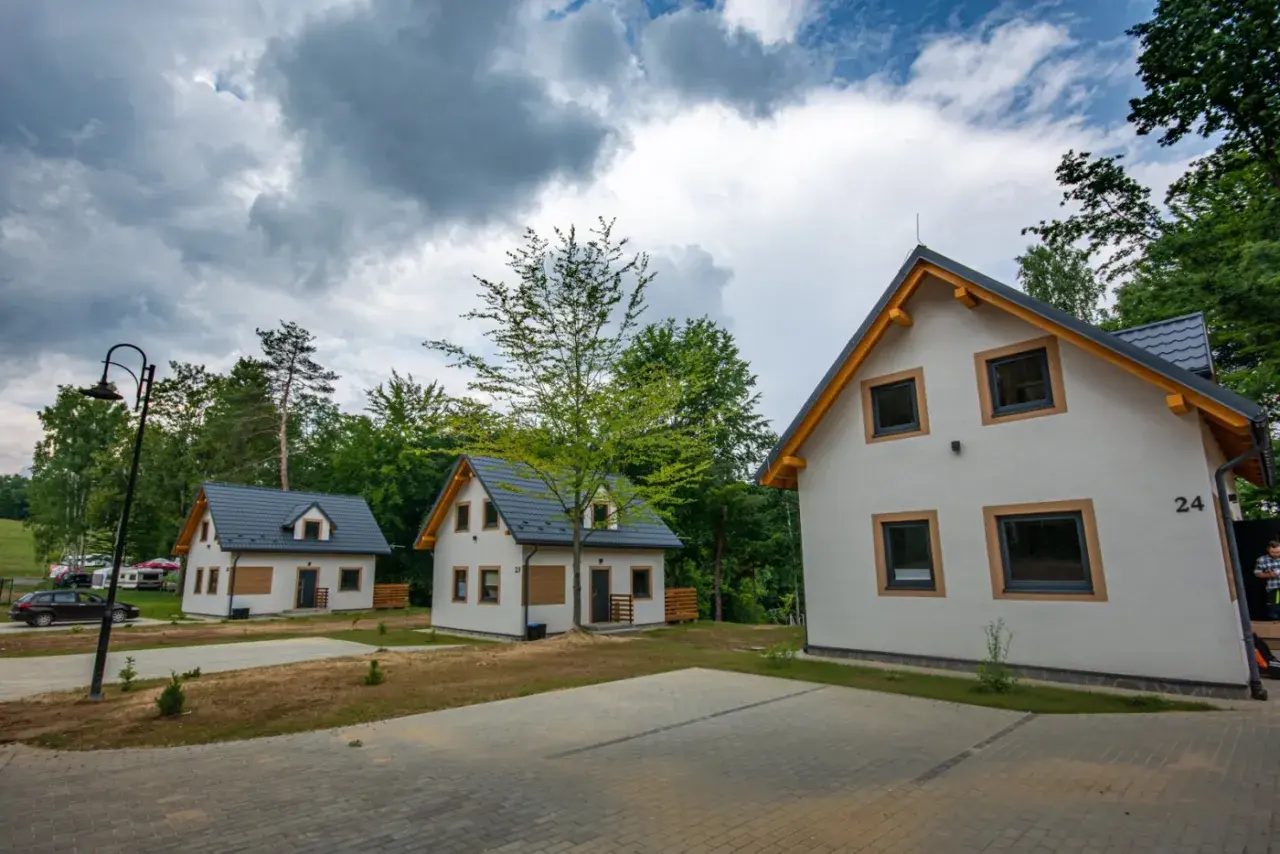 Nowe domki letniskowe, idealne na przystań wyspa energetyk. W tle las i chmury.
