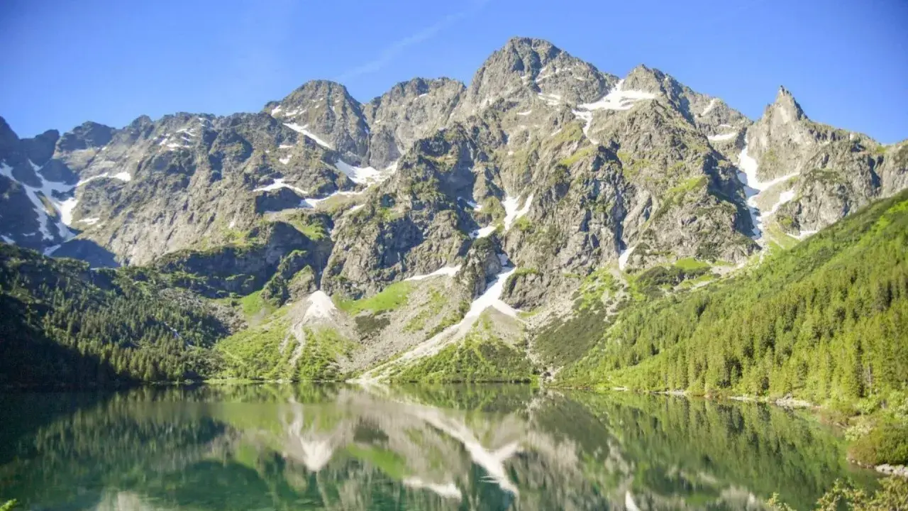 Majestatyczne Tatry odbijają się w spokojnej tafli jeziora. Ciekawe ciekawostki o tatrach czekają na odkrycie!