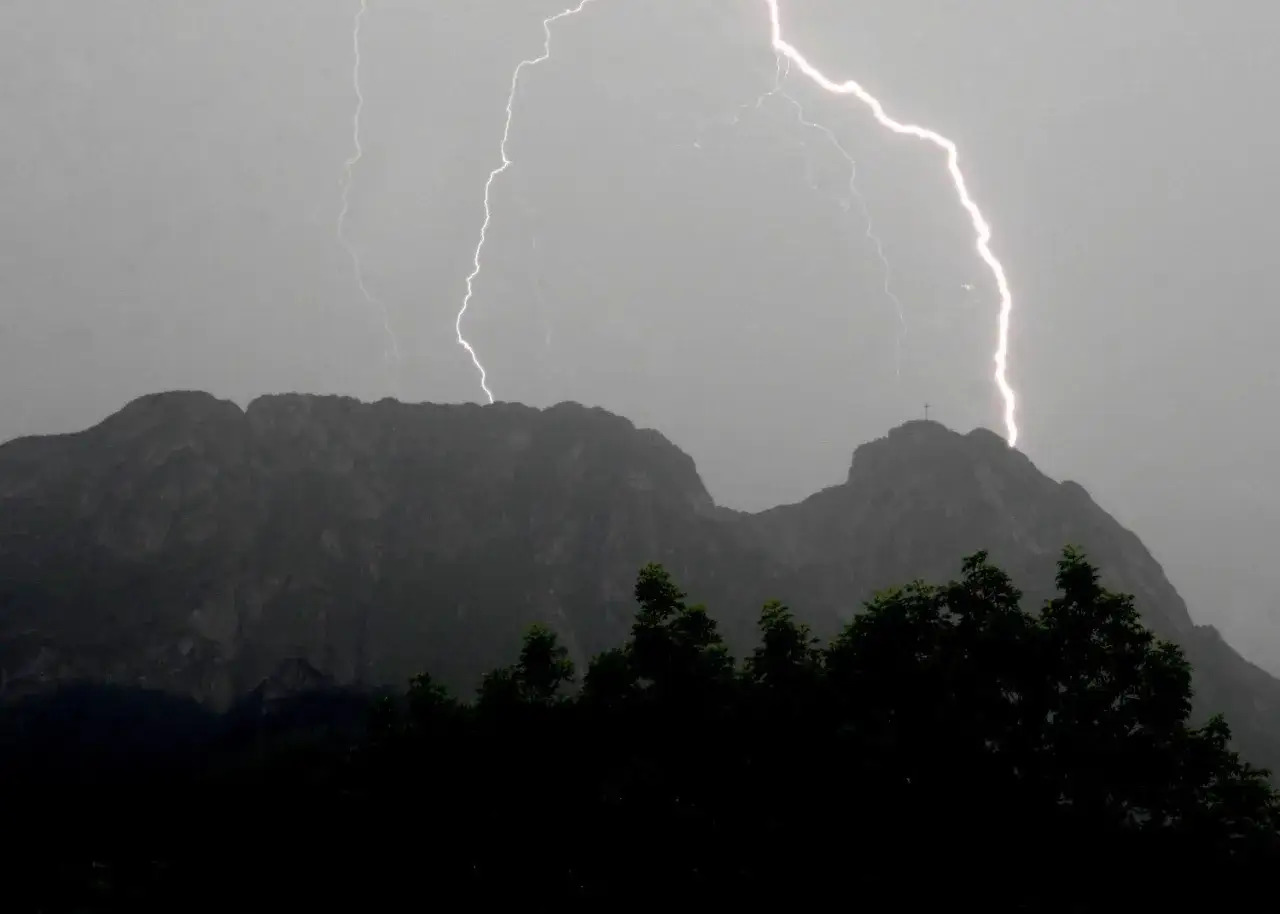 Błyskawice rozświetlają niebo nad Tatrami, jakby budziły śpiącego rycerza. Na szczycie majaczy krzyż.