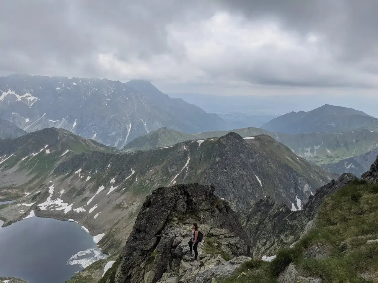 Widok na Tatry z grani, z jeziorem i turystką na skale. Wejście na Zawrat.
