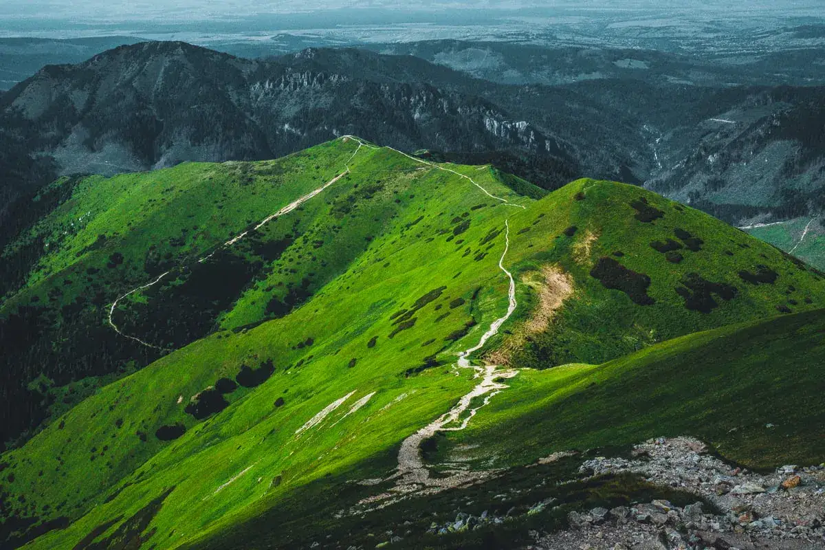 Zielone, pofałdowane zbocza górskie z wijącą się ścieżką. Trzydniowiański wierch trasa zaprasza do wędrówki.