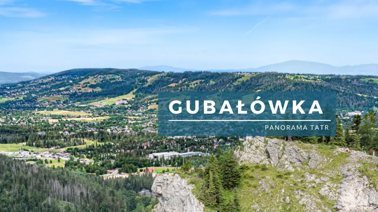 Widok na Gubałówkę z panoramą Tatr. Widoczny czarny szlak prowadzący na szczyt, otoczony zielenią i górami.