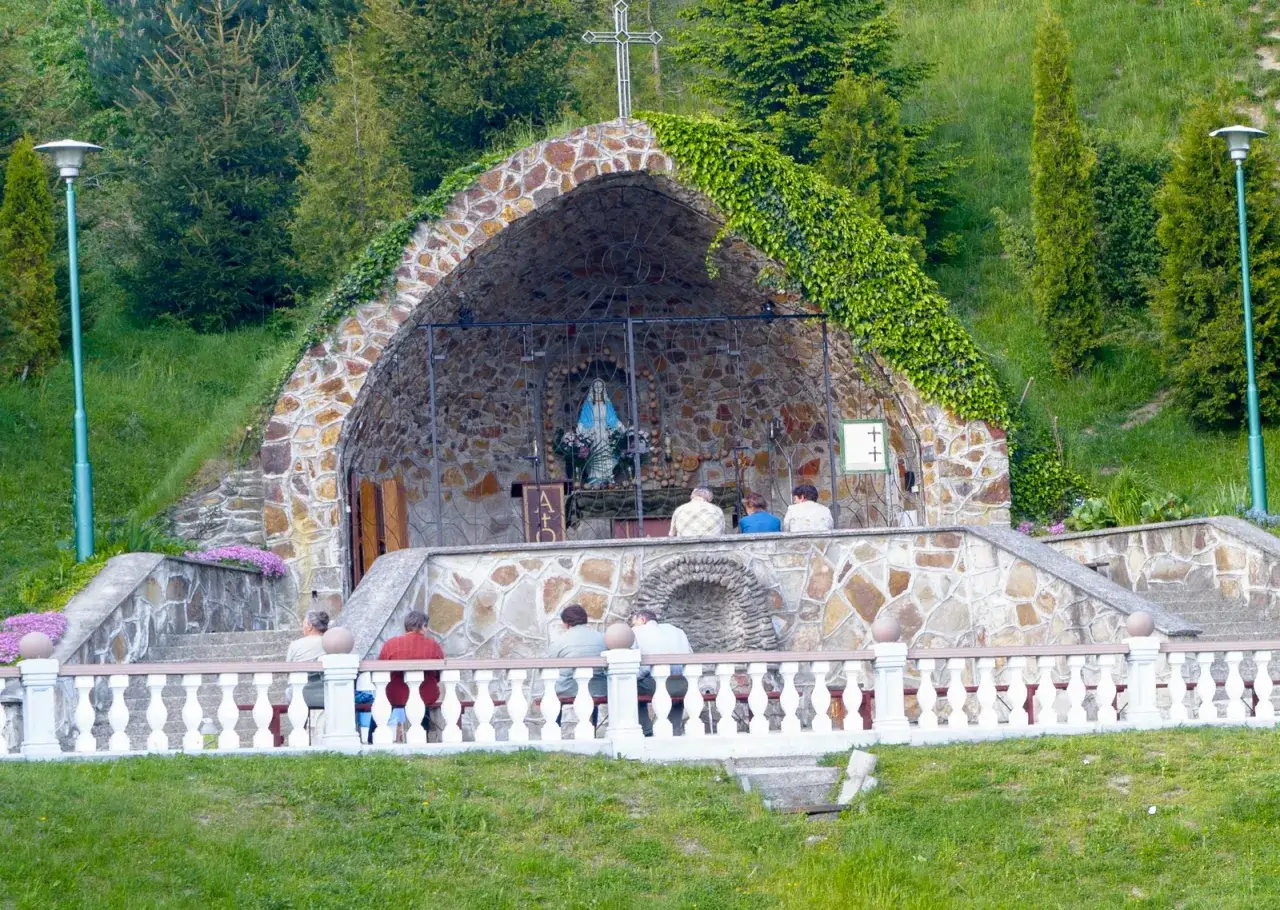 Kamienna grota z figurą Matki Boskiej, otoczona zielenią, to cudowne źródełko w Zwierzyniu. Pielgrzymi w ciszy modlą się przy nim.