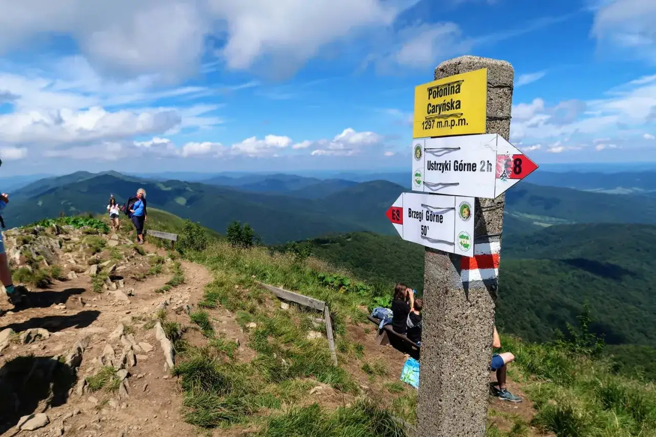 Szlak w Bieszczadzkim Parku Narodowym. Znak informuje o szczycie Połonina Caryńska (1297 m n.p.m.) i kierunkach do Ustrzyk Górnych (2h) i Brzegów Górnych (50').