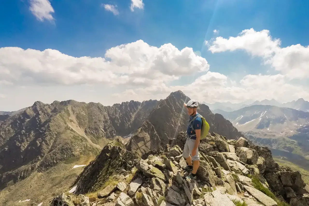 Mężczyzna na szczycie, wskazujący na majestatyczne Tatry Wysokie. Widok zapiera dech w piersiach, idealny na tatrzańskie szlaki.