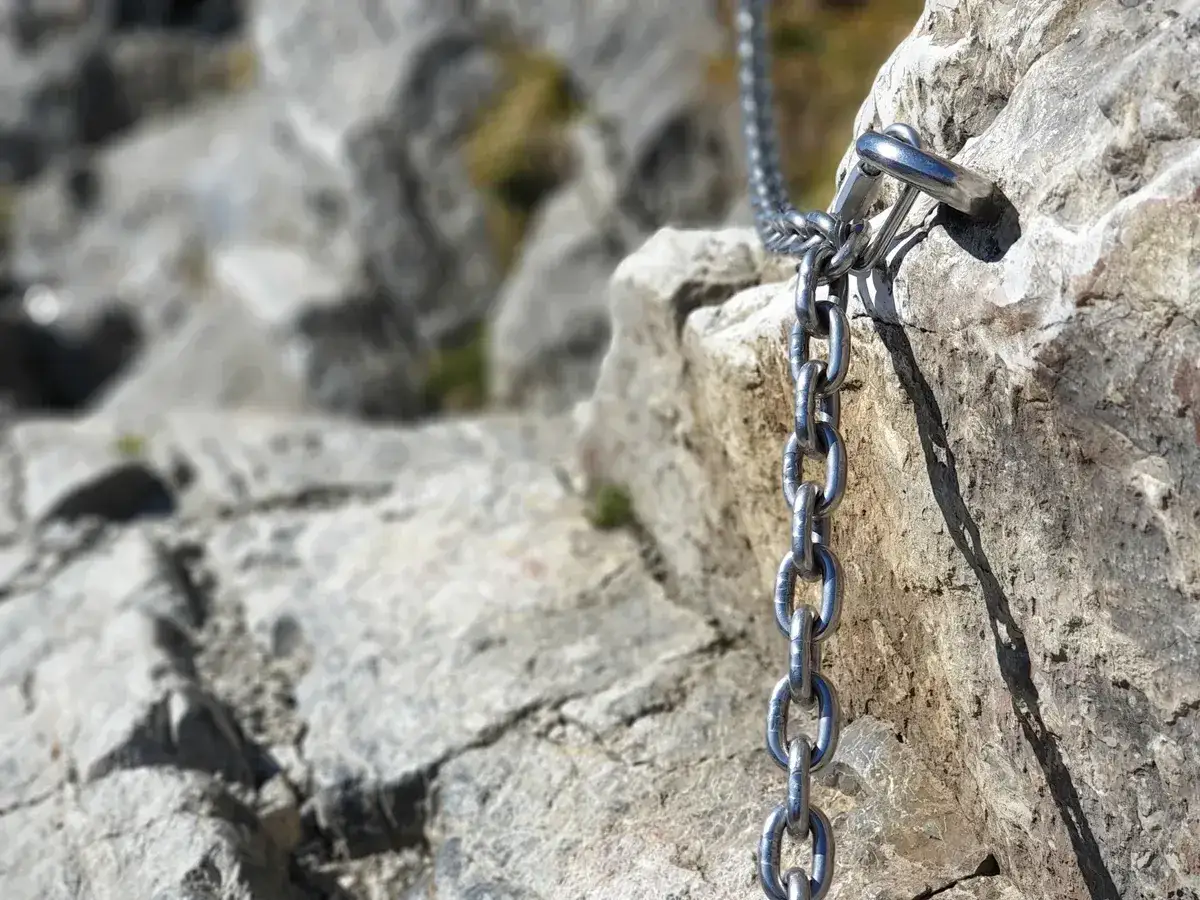 Metalowa łańcuch ułatwia wspinaczkę na skalistym, stromym zboczu. To fragment niebieskiego szlaku na Giewont, zapewniający bezpieczeństwo podczas wędrówki.