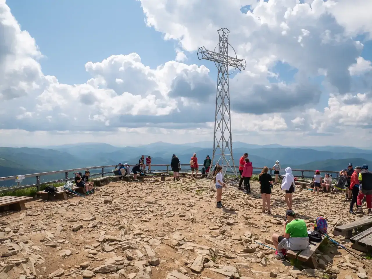 Krzyż na Tarnicy, symbol Bieszczad, góruje nad turystami podziwiającymi rozległą panoramę.