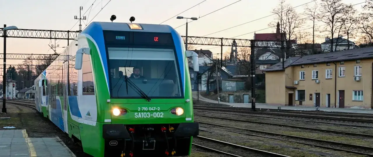 Zielony pociąg PKP stoi na stacji Ustrzyki Dolne. W kabinie maszynista.