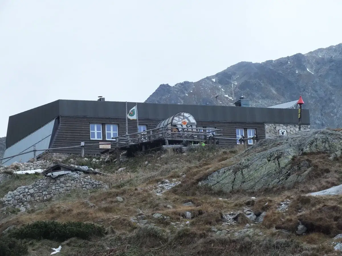 Zbójnicka chata Tatry, drewniany budynek z oknami i tarasem, na tle skalistych gór.